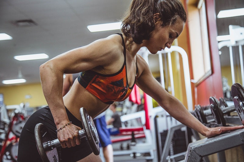 fit woman lifting dumbbell in gym